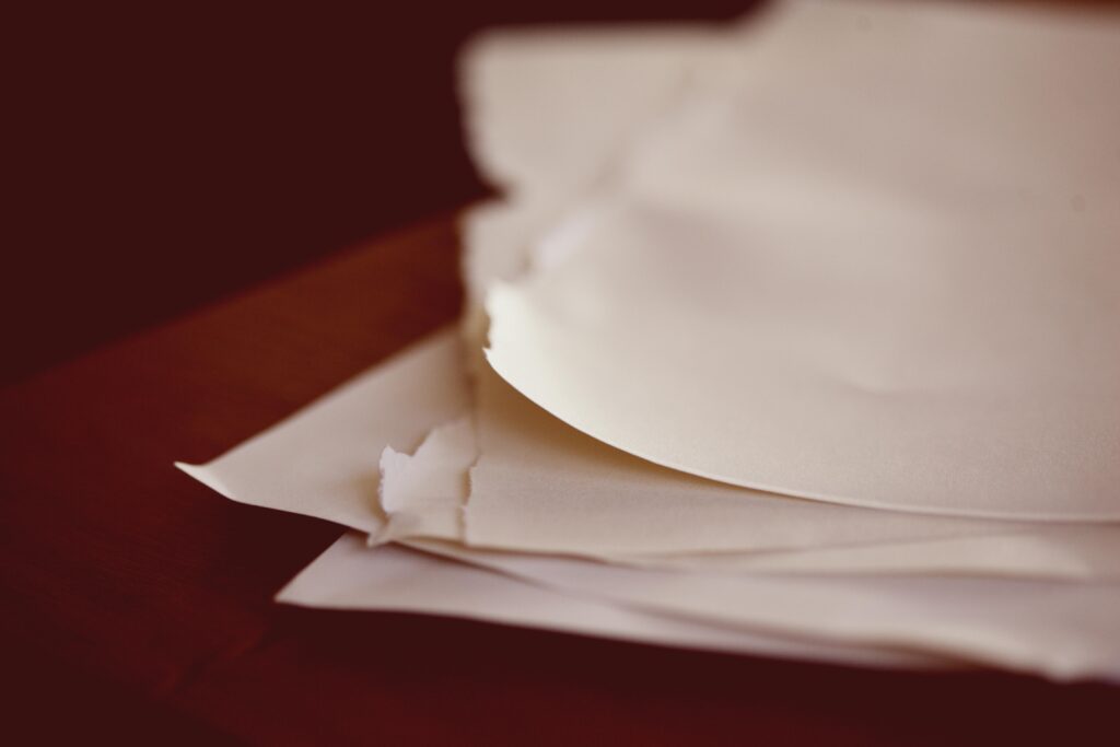 A close-up view of torn papers stacked on a desk with a blurred background.